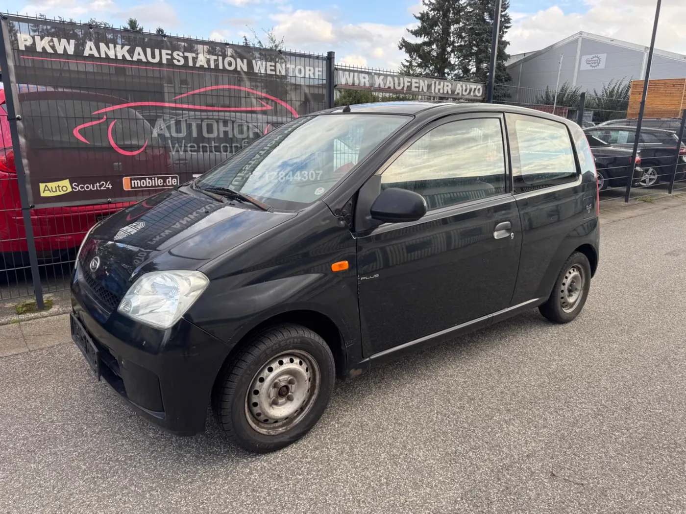 Hofzaun am Südring 40 mit dem Banner „PKW Ankaufstation Wentorf · Wir kaufen Ihr Auto“, davor ein Kleinwagen